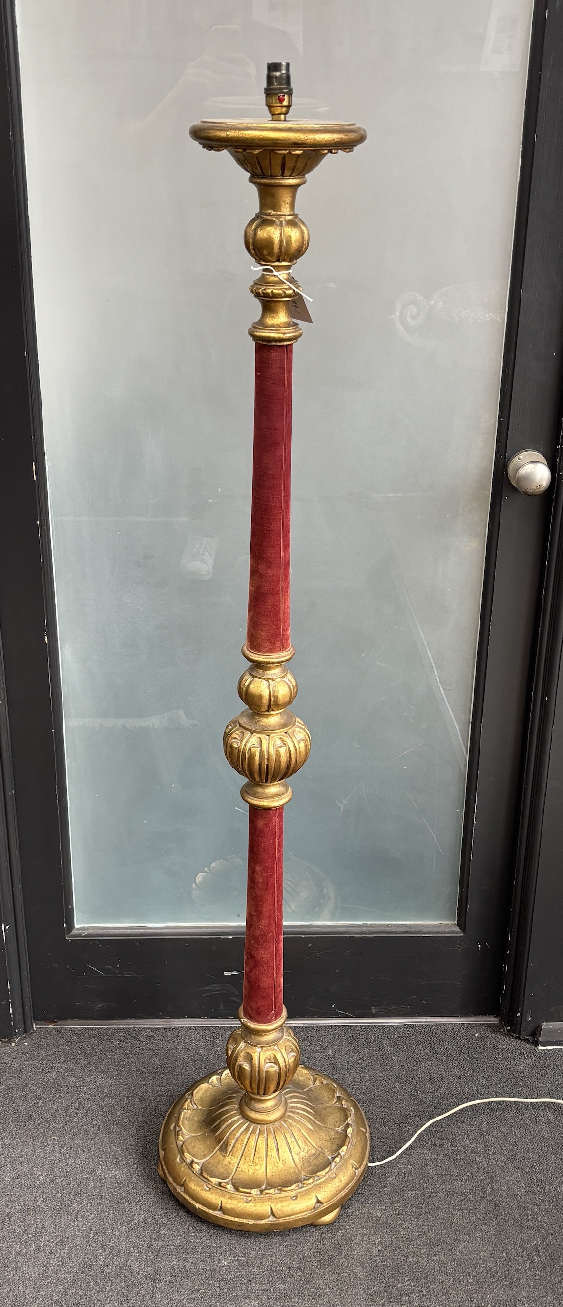 A gilt standard lamp with part fabric covered column
